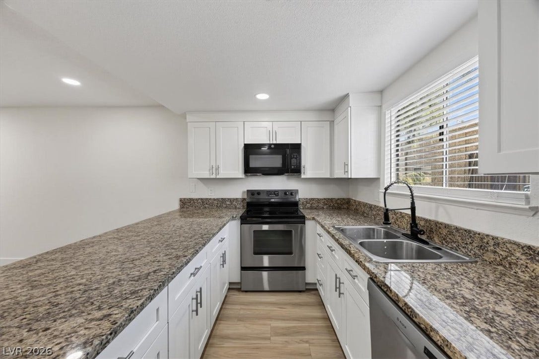 4454 W Desert Inn Road, #D, Las Vegas, NV 89102 Polished granite countertops surround a functional workspace anchored by durable wood-look flooring.