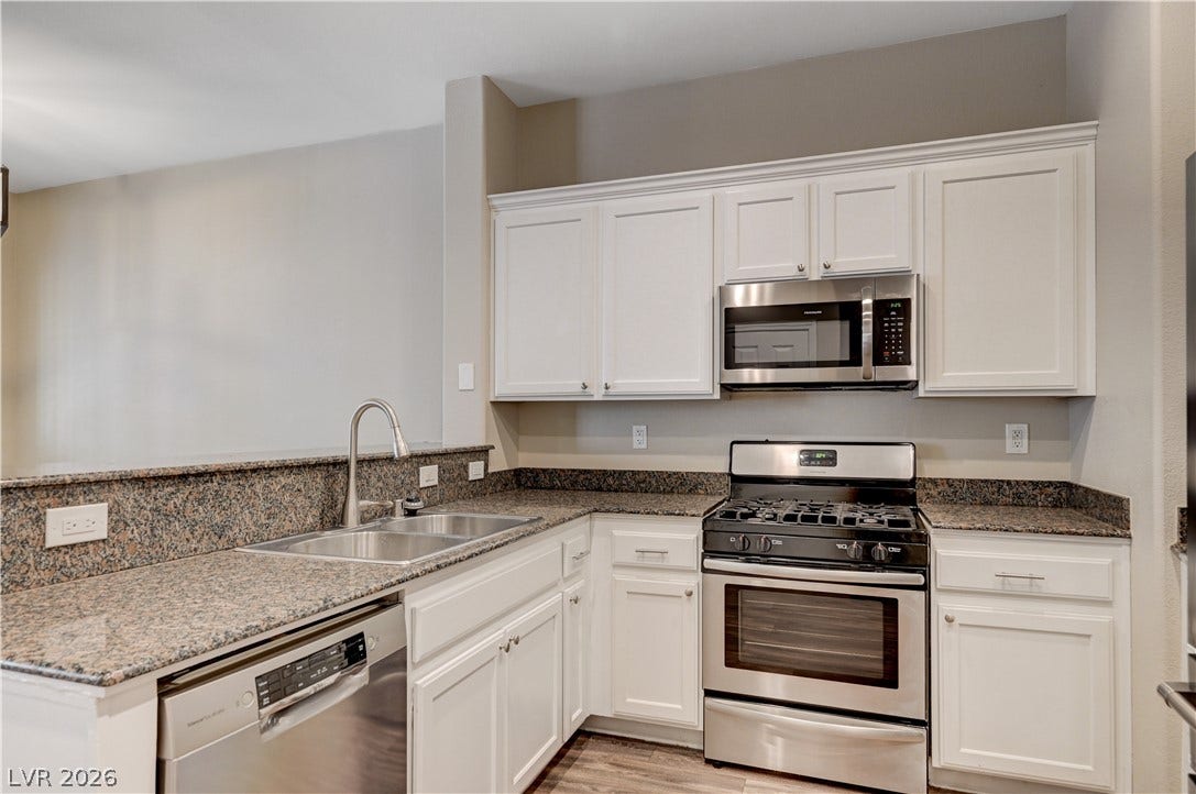 1525 Spiced Wine Avenue, #3105, Henderson, NV 89074 Gleaming stone countertops and stainless steel appliances elevate this bright, functional kitchen space.