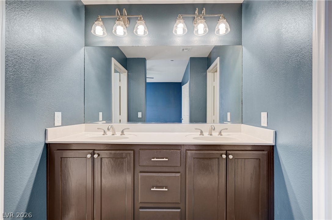 1525 Spiced Wine Avenue, #3105, Henderson, NV 89074 Dual sinks sit beneath a wide mirror and bright vanity lights.