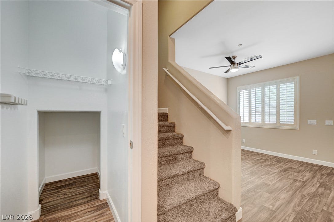 1525 Spiced Wine Avenue, #3105, Henderson, NV 89074 A carpeted staircase sits adjacent to under-stair storage and a wood-look vinyl floored living area.