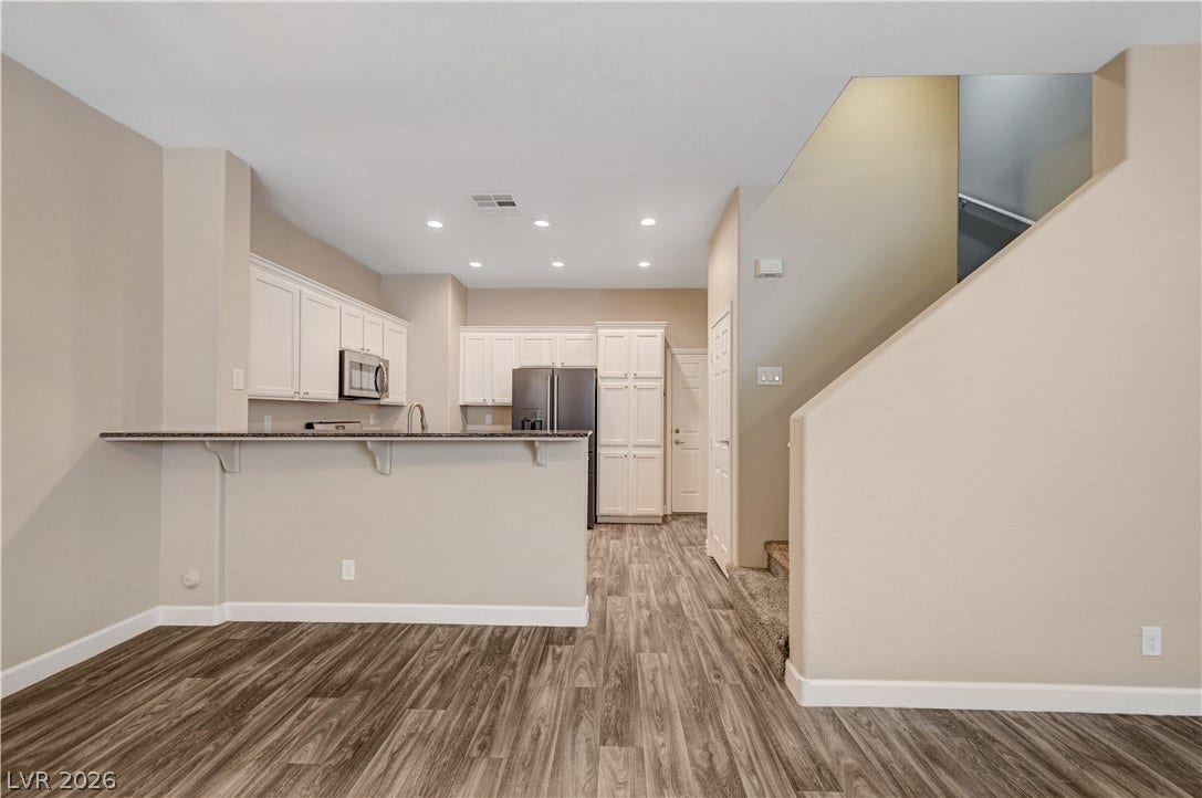 1525 Spiced Wine Avenue, #3105, Henderson, NV 89074 An open floorplan seamlessly connects the kitchen with modern wood-patterned flooring and adjacent staircase.