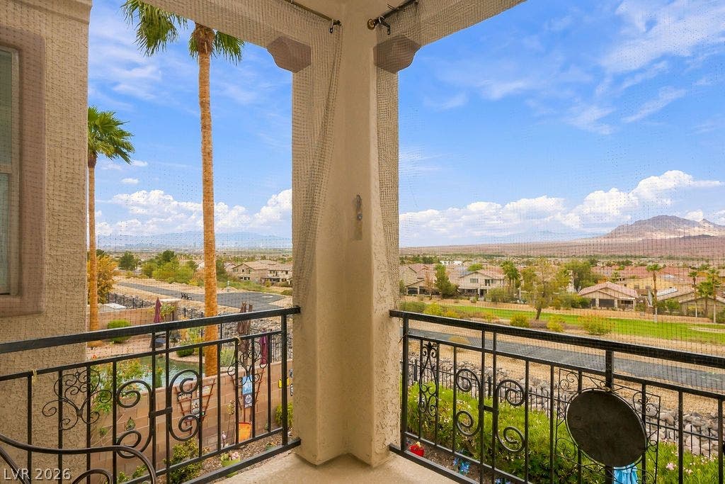 Panoramic mountain and valley vistas unfold from this elevated covered balcony with wrought iron railings.