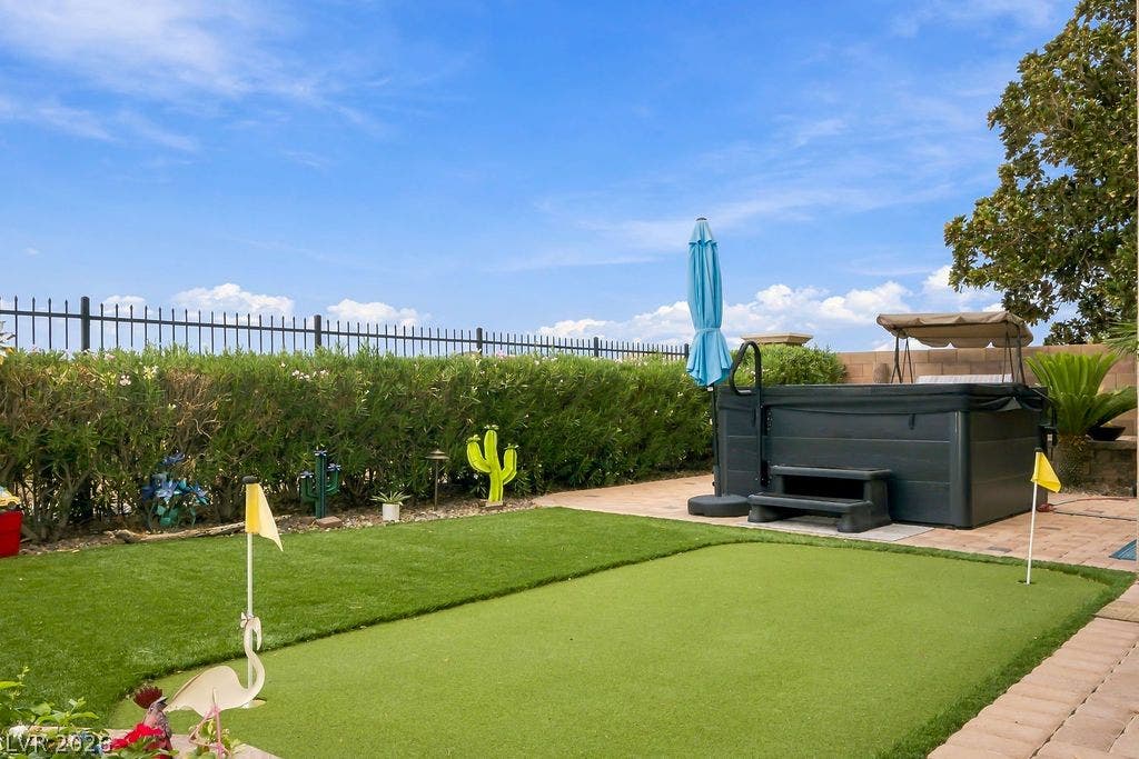 Manicured putting green pairs with an outdoor spa under a vast blue sky.
