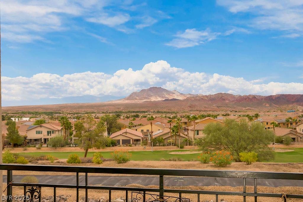 A sweeping panorama captures distant desert peaks, manicured golf fairways, and endless blue sky.