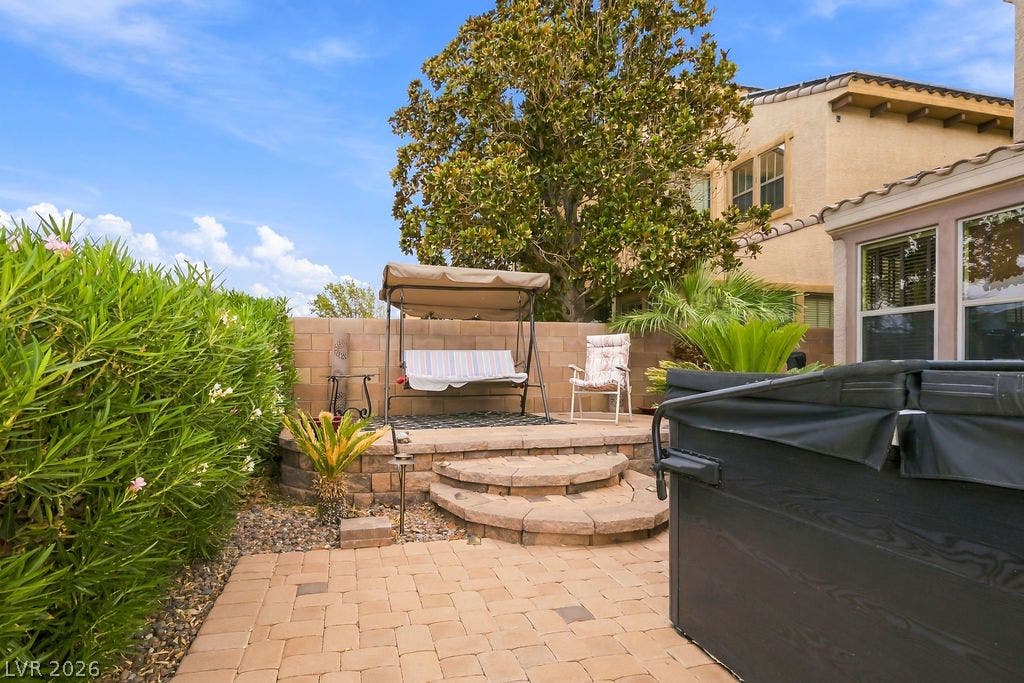 An inviting backyard patio features elegant brick pavers and a raised stone terrace.