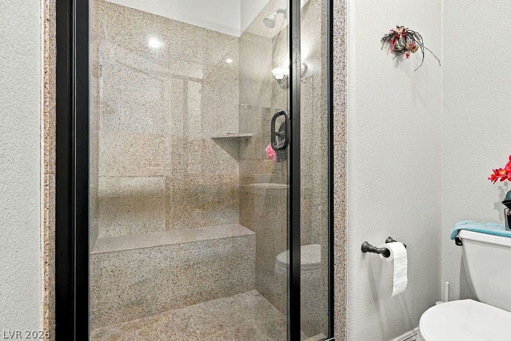 Polished stone surfaces enclose a spacious walk-in shower featuring a built-in bench seat.