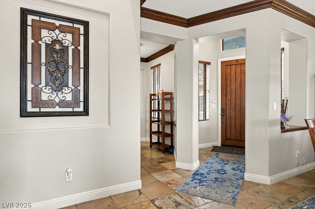 Rich wood crown molding and warm tile floors guide visitors through a welcoming entryway.