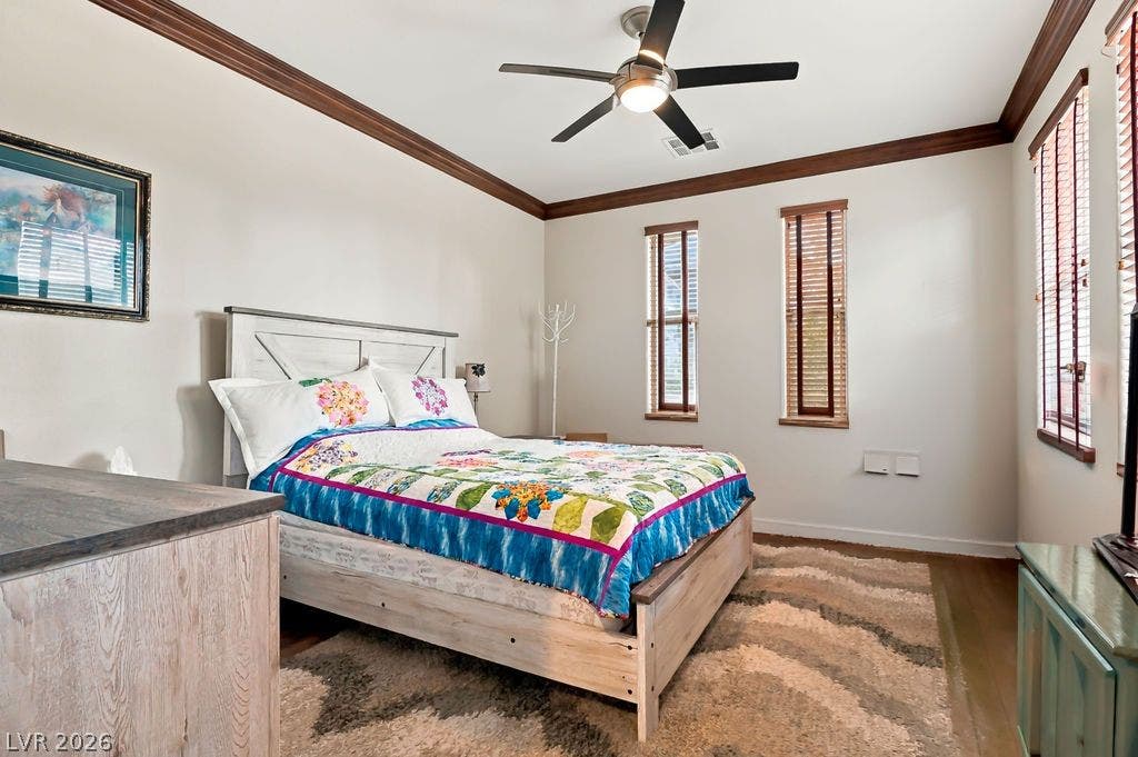 Warm hardwood floors and classic crown molding define this welcoming bedroom space.