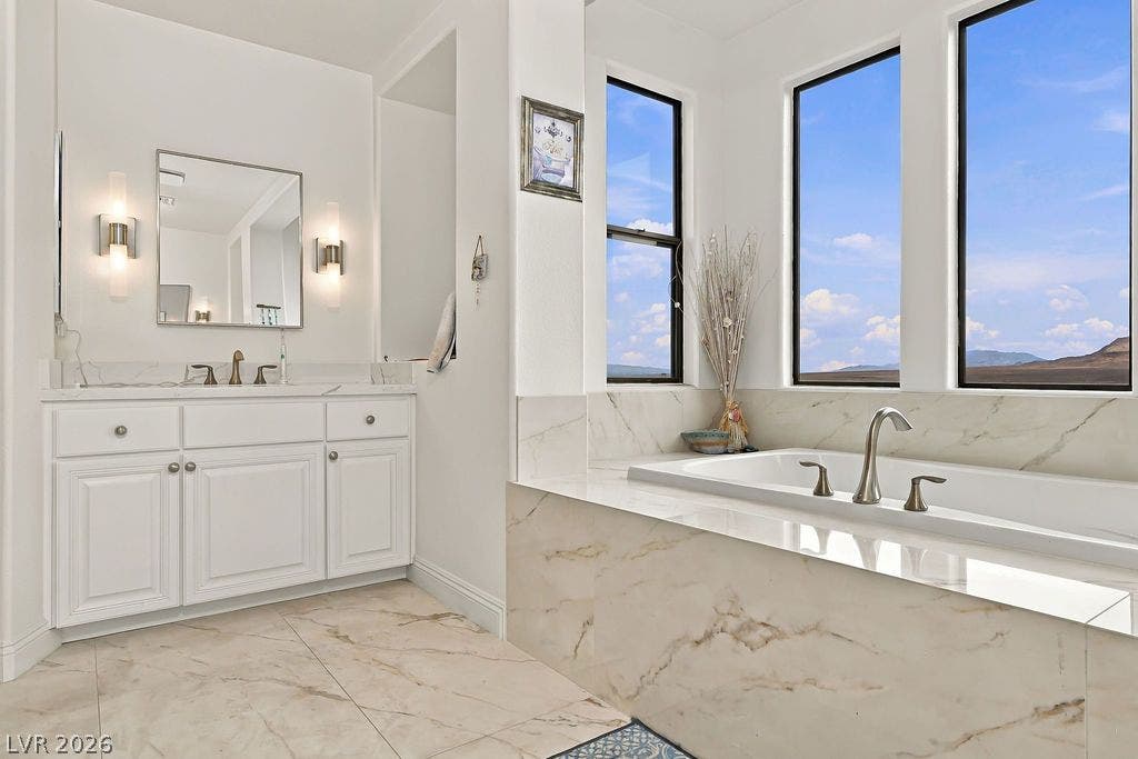 A deep soaking tub sits under large windows overlooking expansive mountain and desert views.