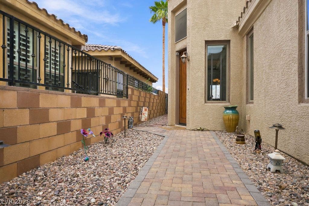 A paved walkway guides the way alongside stucco walls and block fencing.