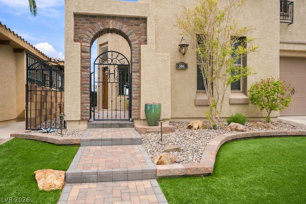 An arched brick entryway with a wrought-iron gate leads into a private front courtyard.