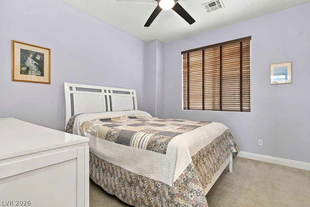 Carpeted floors and a classic window frame highlight this comfortable bedroom space.