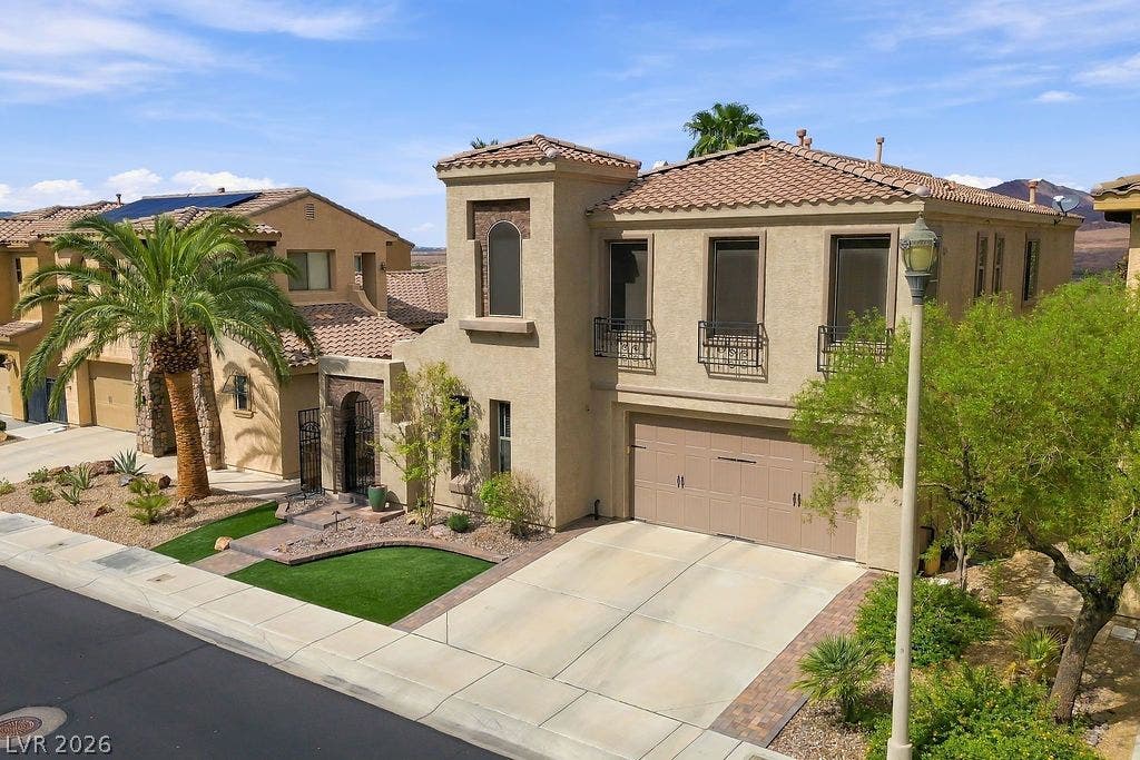 Spanish-style architecture highlights this multi-level exterior featuring a barrel tile roof and concrete driveway.