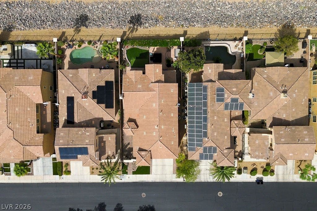 An aerial perspective showcases a neat row of homes with tiled roofs and backyard pools.