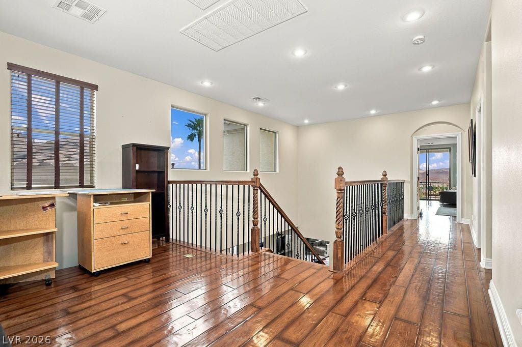 Rich hardwood flooring and recessed lighting define this spacious upstairs landing area.