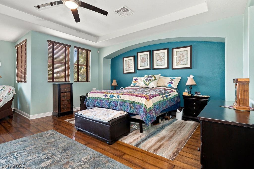Rich hardwood flooring complements the tray ceiling and elegant arched wall niche.