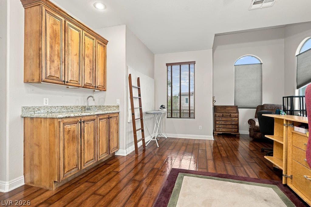 Warm wood flooring and detailed built-in cabinetry enhance this versatile home office environment.