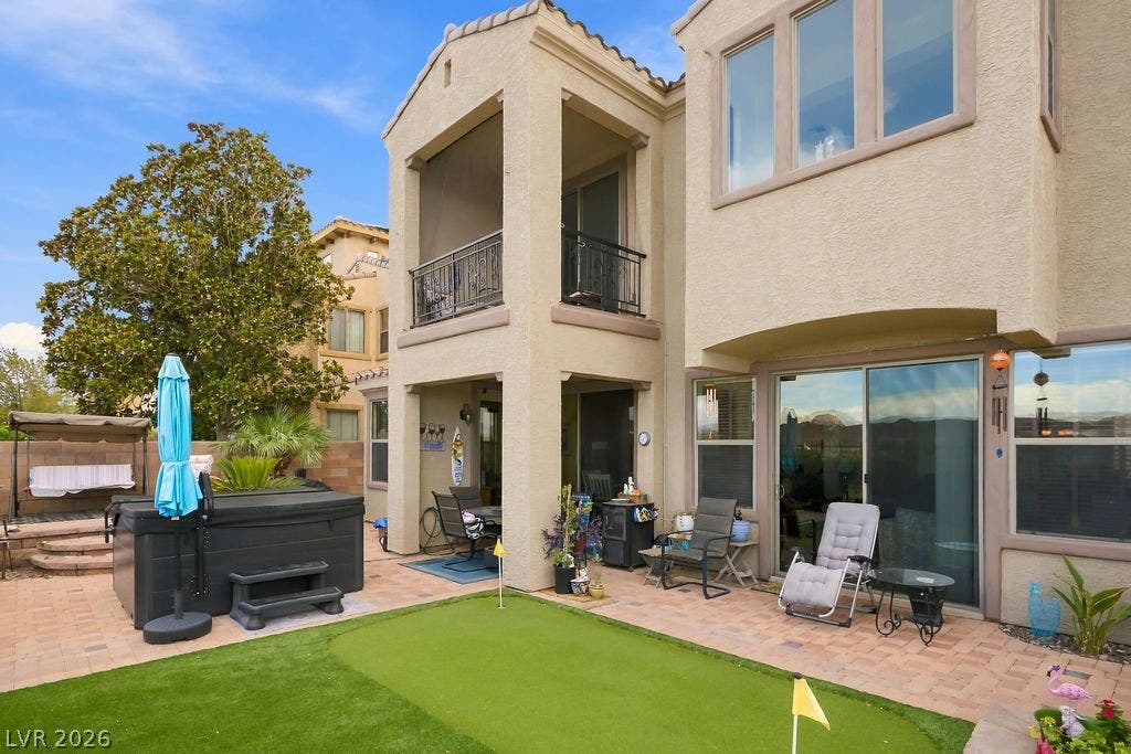 Multi-level stucco exterior opens directly to a paved patio and private backyard putting green.