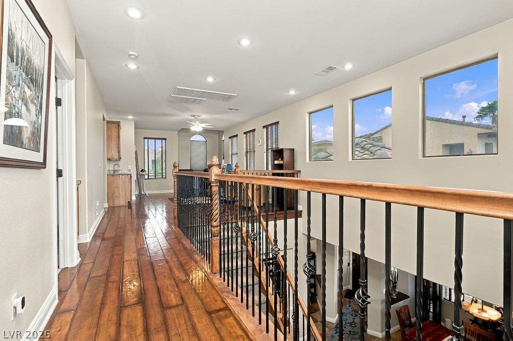 Rich hardwood floors and soaring ceilings define this airy upper-level landing and open hallway.