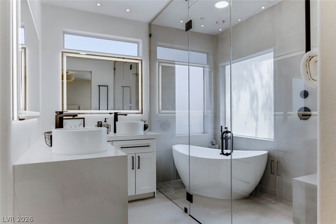 2601 Arimo Drive, Henderson, NV 89052 A freestanding soaking tub stands inside a glass-enclosed shower wet room with dual vessel sink vanities.