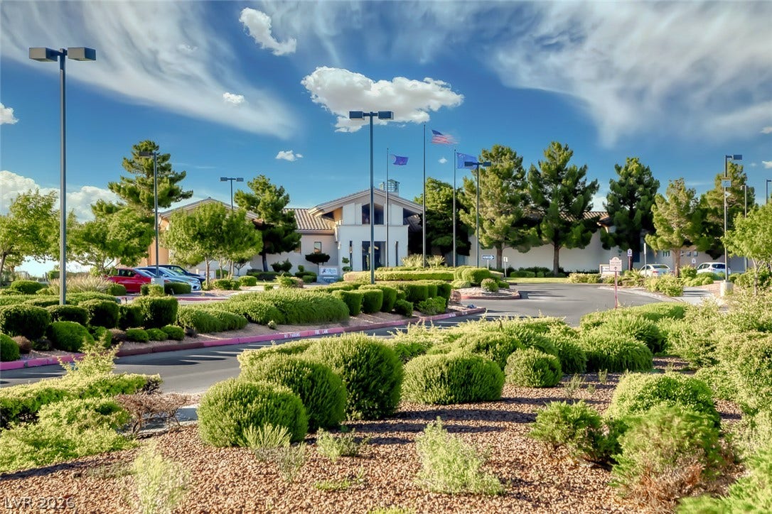 2601 Arimo Drive, Henderson, NV 89052 Lush desert landscaping and mature trees frame the grand community building under vibrant blue skies.