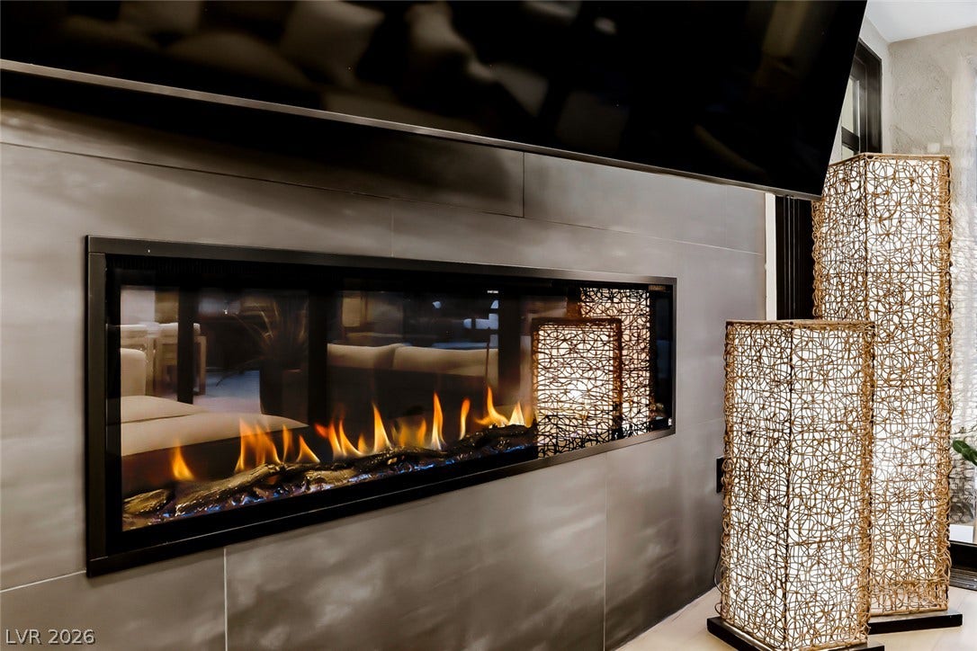 2601 Arimo Drive, Henderson, NV 89052 A modern linear fireplace inset within a sleek tiled wall anchor the space.