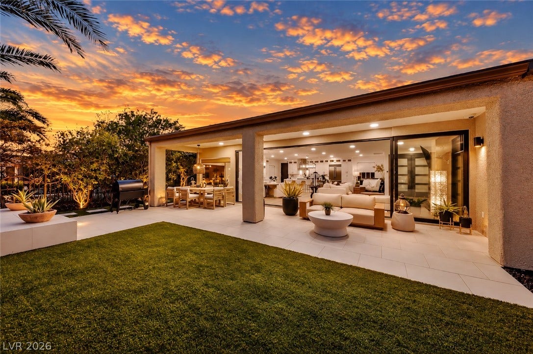 2601 Arimo Drive, Henderson, NV 89052 An expansive covered patio overlooks a manicured lawn under a sunset sky.