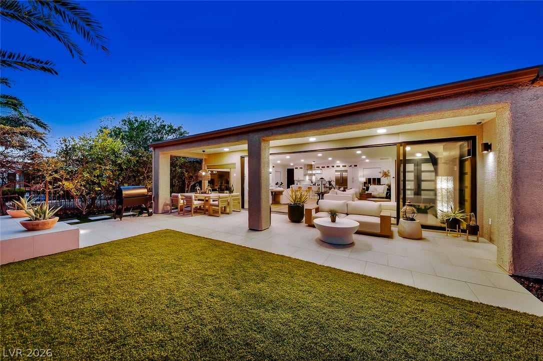 2601 Arimo Drive, Henderson, NV 89052 A spacious covered patio seamlessly transitions to a manicured lawn under the evening sky.