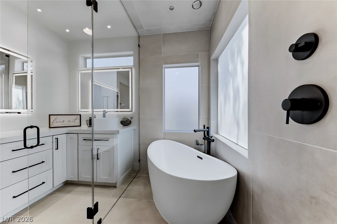 2601 Arimo Drive, Henderson, NV 89052 A sleek freestanding soaking tub rests beneath frosted windows in this contemporary bathroom.
