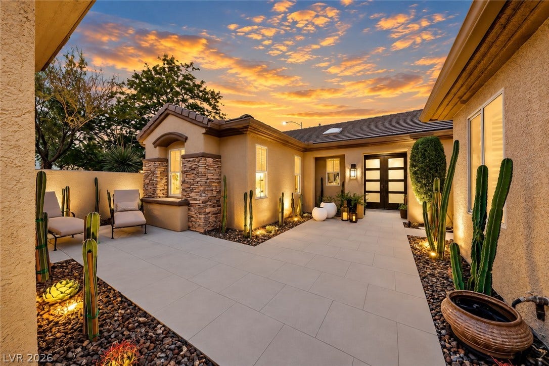 2601 Arimo Drive, Henderson, NV 89052 An inviting gated courtyard features modern stone paving and desert-inspired landscaping under a dramatic sunset sky.