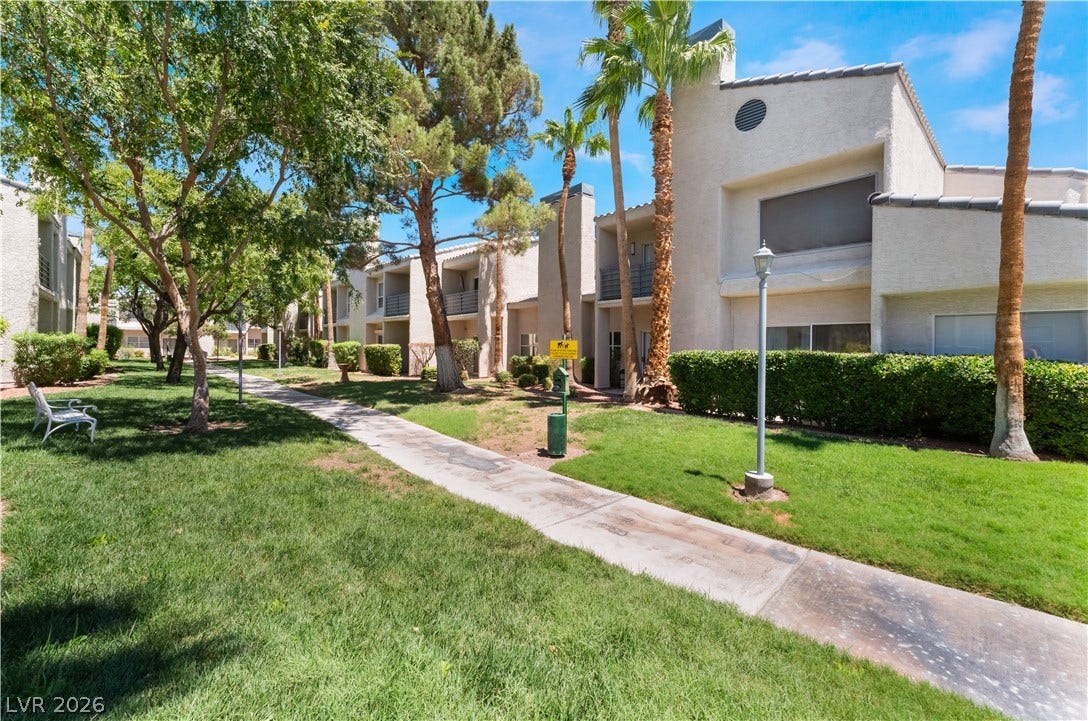 6250 W Flamingo Road, #37, Las Vegas, NV 89103 A vibrant green lawn and well-maintained buildings line a sunny pathway, creating an inviting community setting.