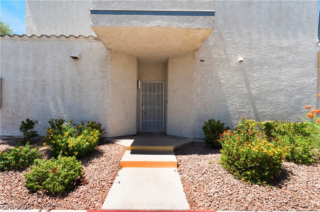 6250 W Flamingo Road, #37, Las Vegas, NV 89103 A welcoming entry features a secure gate, leading to a home nestled amongst vibrant landscaping.
