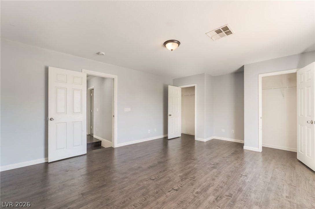 Unfurnished bedroom featuring dark wood-style floors and multiple closets