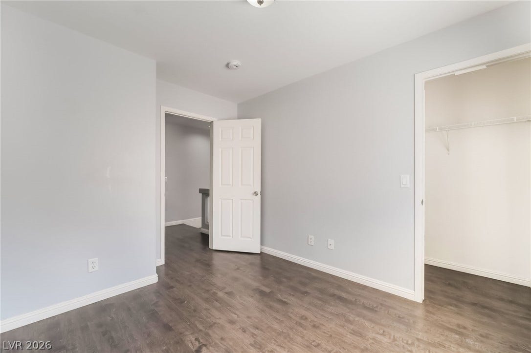 Unfurnished bedroom with a spacious closet and dark wood finished floors