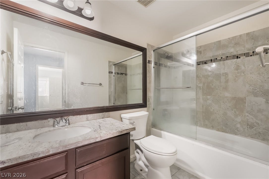 Bathroom with combined bath / shower with glass door, vanity, and tile patterned floors