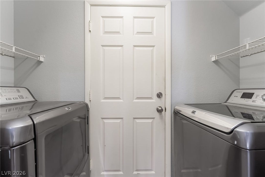 Washroom with washing machine and clothes dryer and a textured wall