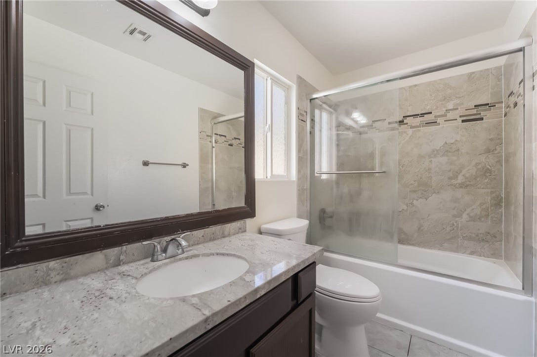 Bathroom with enclosed tub / shower combo, vanity, and light tile patterned floors