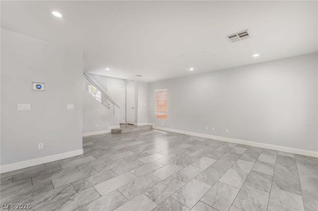 Unfurnished living room featuring recessed lighting and stairway
