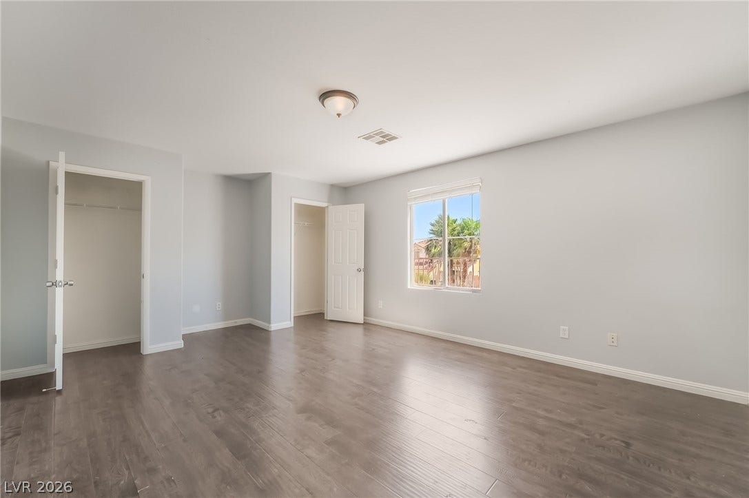 Unfurnished bedroom with multiple closets and dark wood-style flooring
