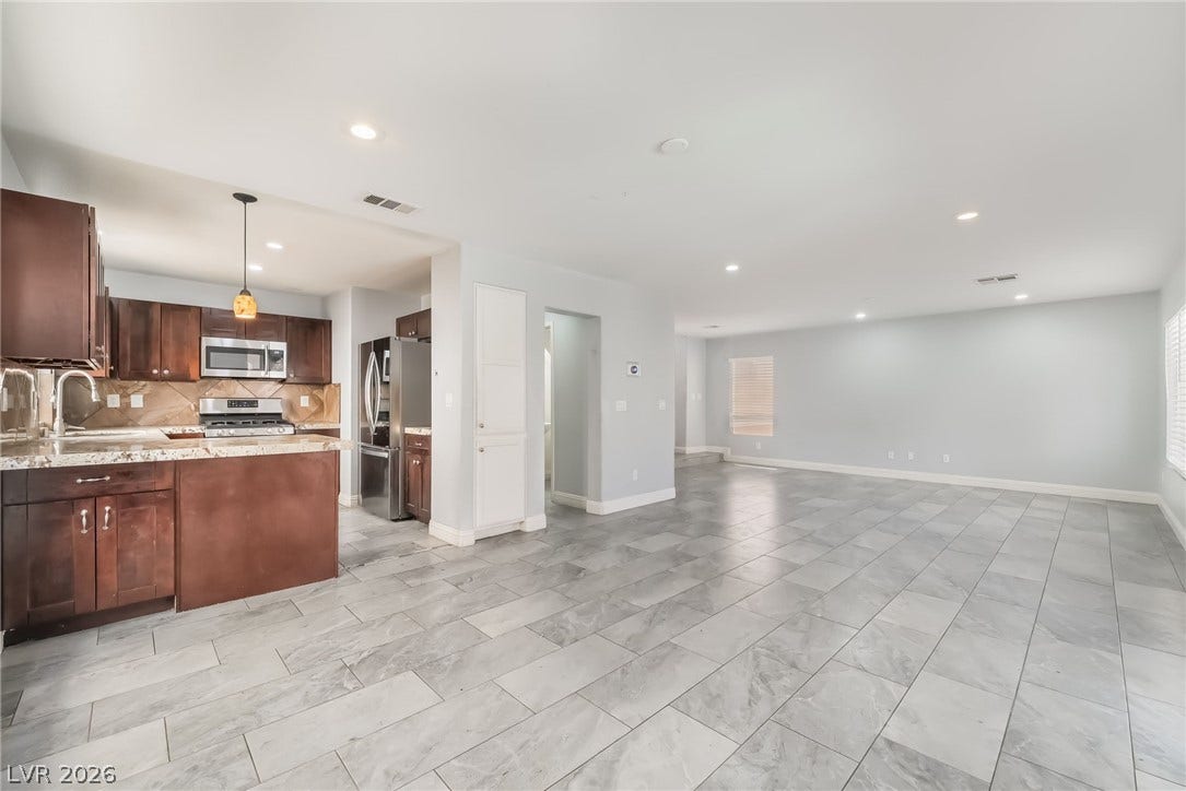 Kitchen featuring backsplash, decorative light fixtures, stainless steel appliances, open floor plan, and light stone counters
