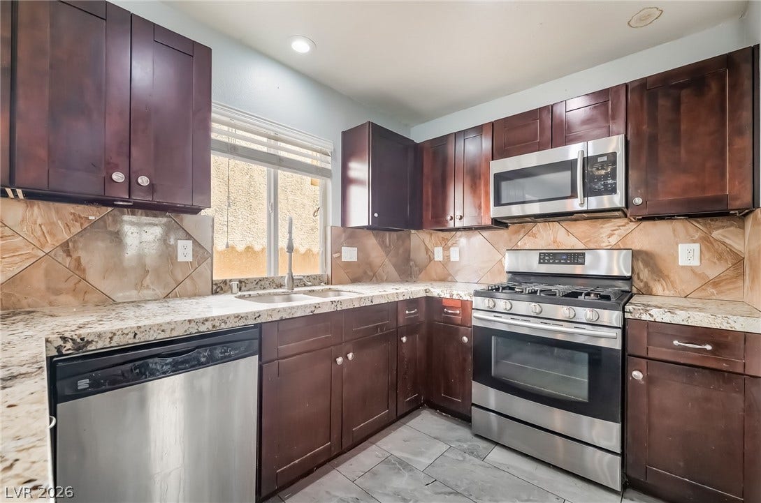 Kitchen featuring appliances with stainless steel finishes, backsplash, light stone countertops, recessed lighting, and dark brown cabinets