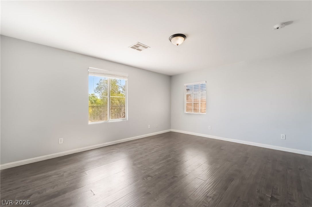 Spare room featuring dark wood-type flooring and baseboards