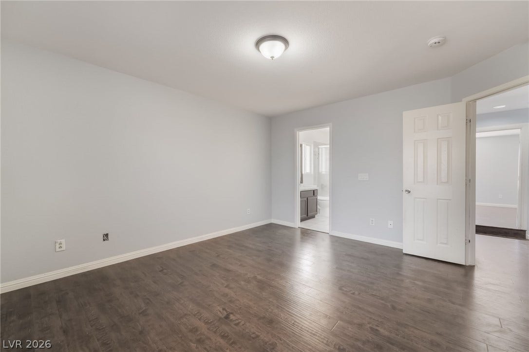 Unfurnished bedroom with dark wood-style flooring and ensuite bathroom