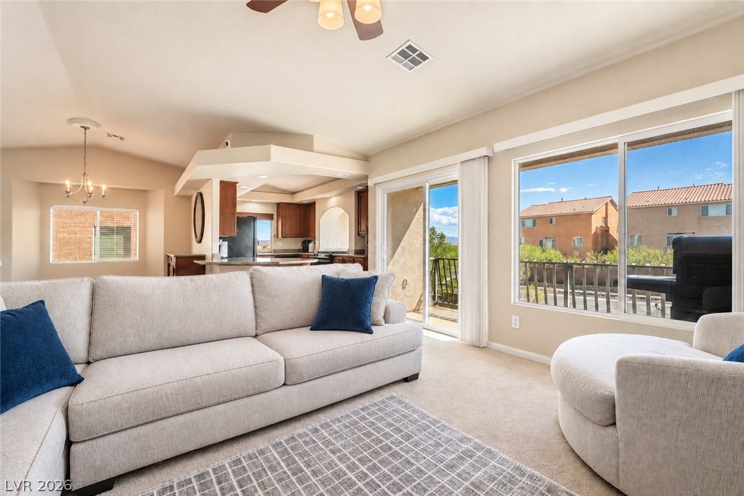 6771 Bravura Court, Las Vegas, NV 89139 Sliding glass doors open to a private balcony from this carpeted living area.