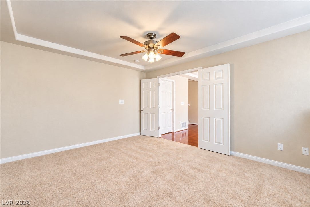 6771 Bravura Court, Las Vegas, NV 89139 Double doors open to a carpeted bedroom with tray ceiling detail and neutral finishes.
