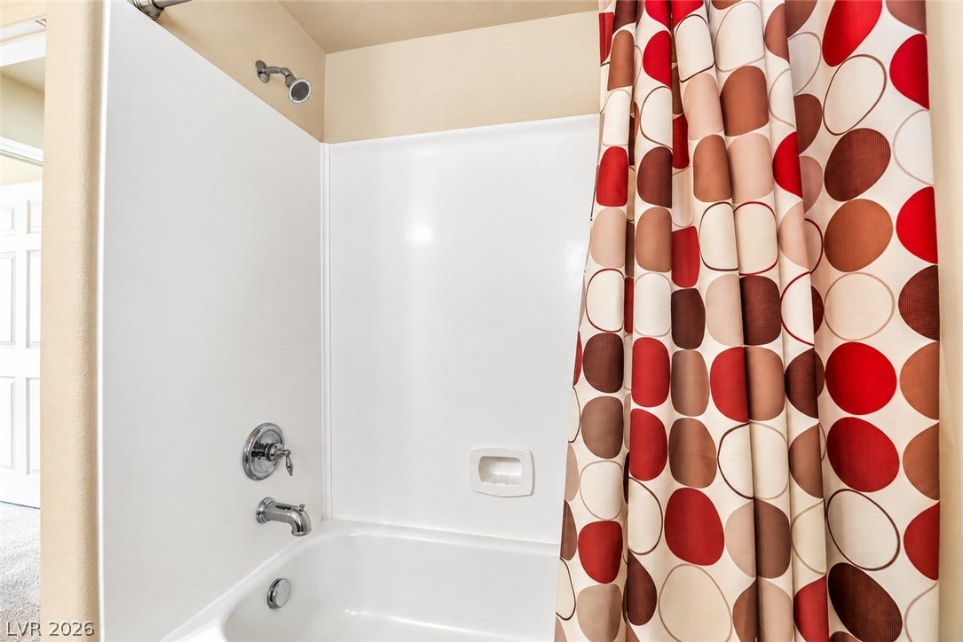 6771 Bravura Court, Las Vegas, NV 89139 A clean white tub shower surround provides easy maintenance in this full bathroom.