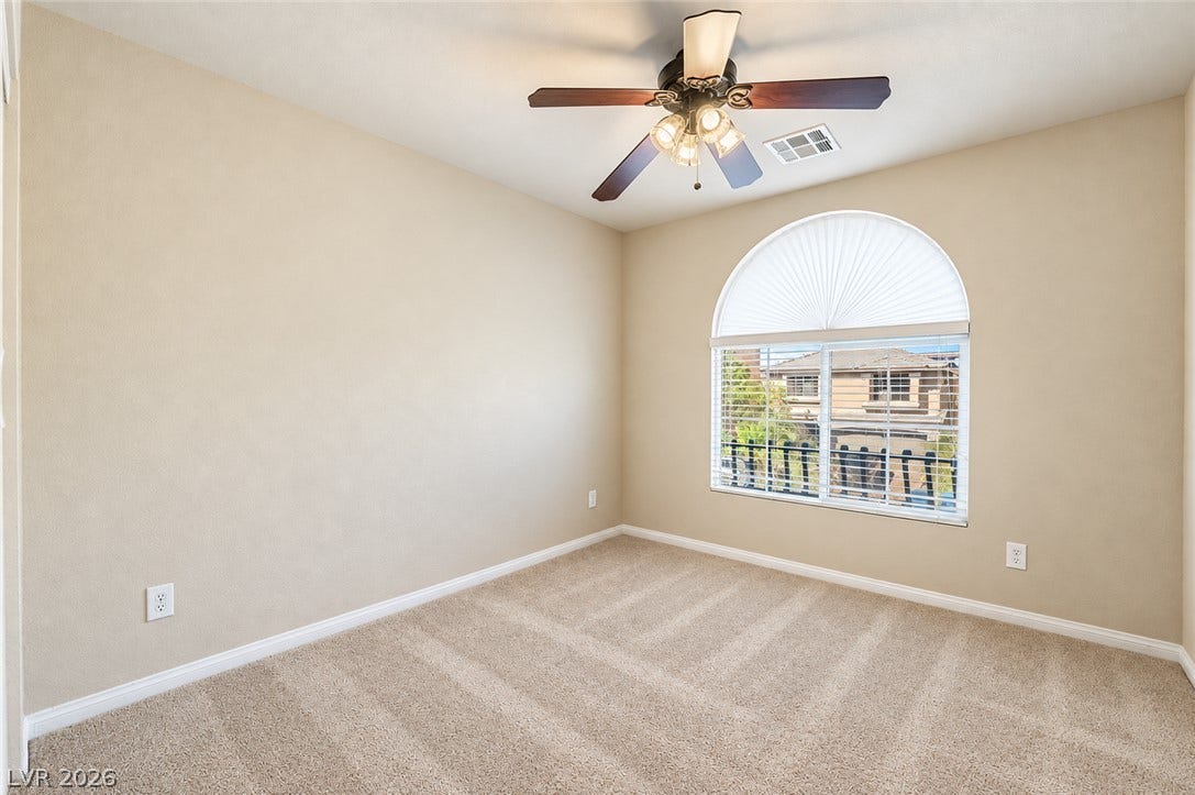 6771 Bravura Court, Las Vegas, NV 89139 Plush carpeting anchors this bright bedroom beneath a classic arched window.