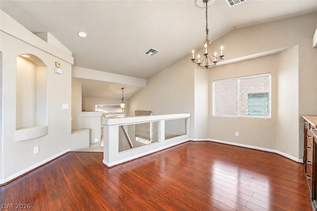 6771 Bravura Court, Las Vegas, NV 89139 Rich hardwood flooring complements the vaulted ceiling and inset wall niches in this open space.