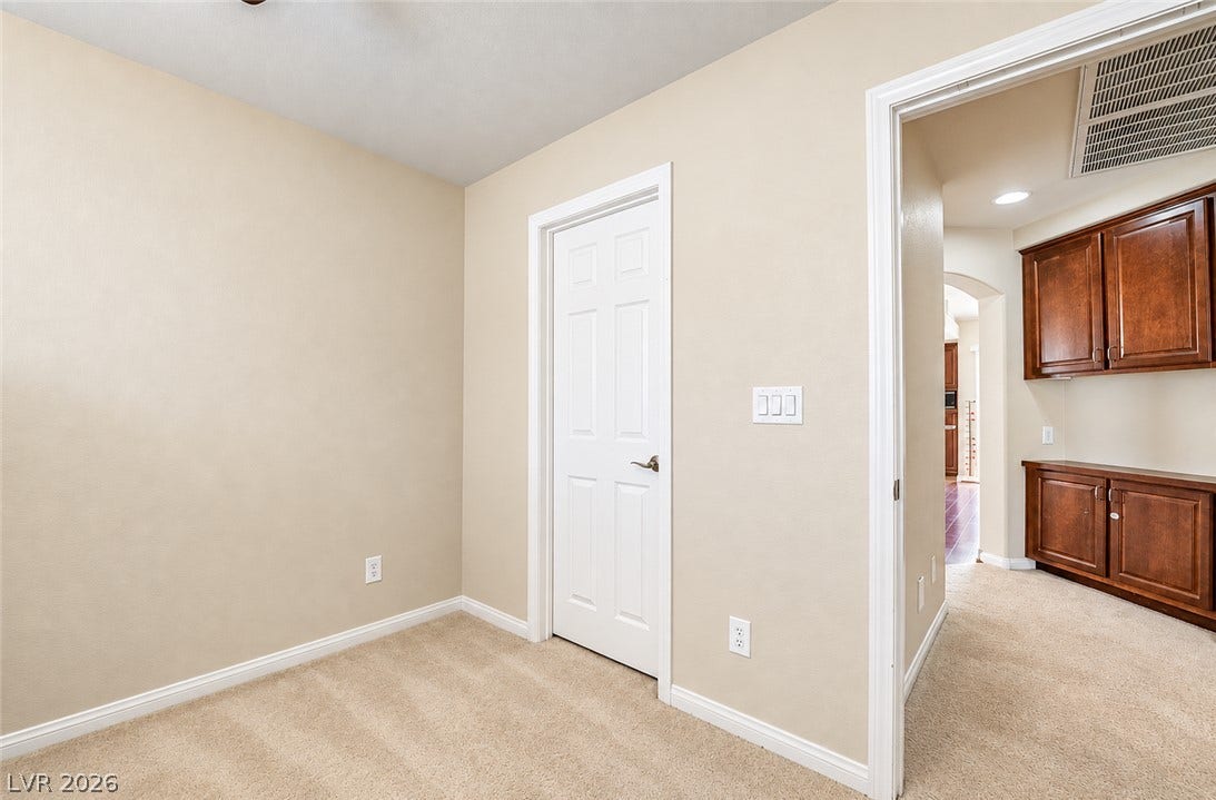 6771 Bravura Court, Las Vegas, NV 89139 Neutral walls and plush carpeting frame a versatile room opening to built-in hallway cabinetry.