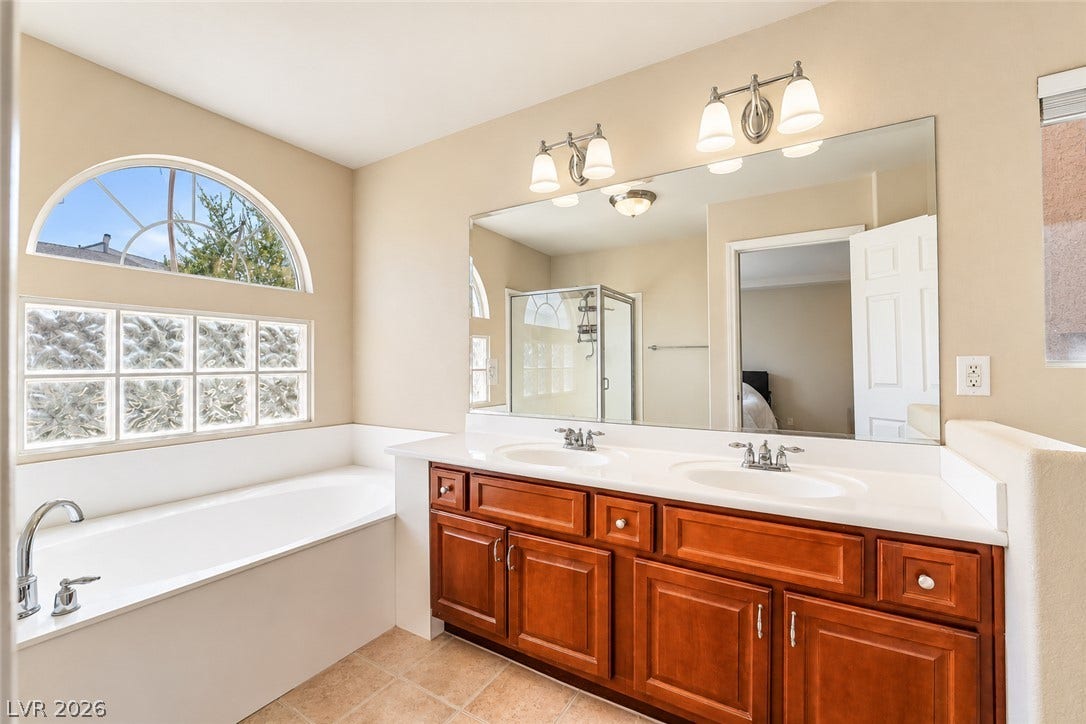 6771 Bravura Court, Las Vegas, NV 89139 Double vanity sinks and a deep soaking tub highlight this spacious bathroom.
